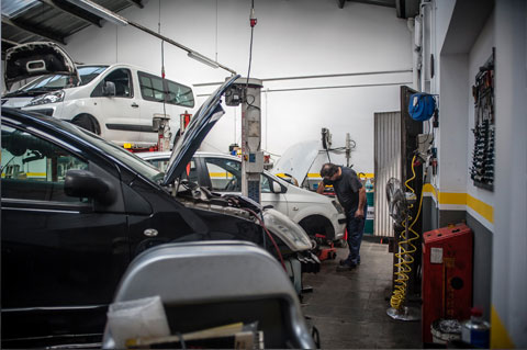 Cotxes amb el capó obert a un taller de reparació de vehícles